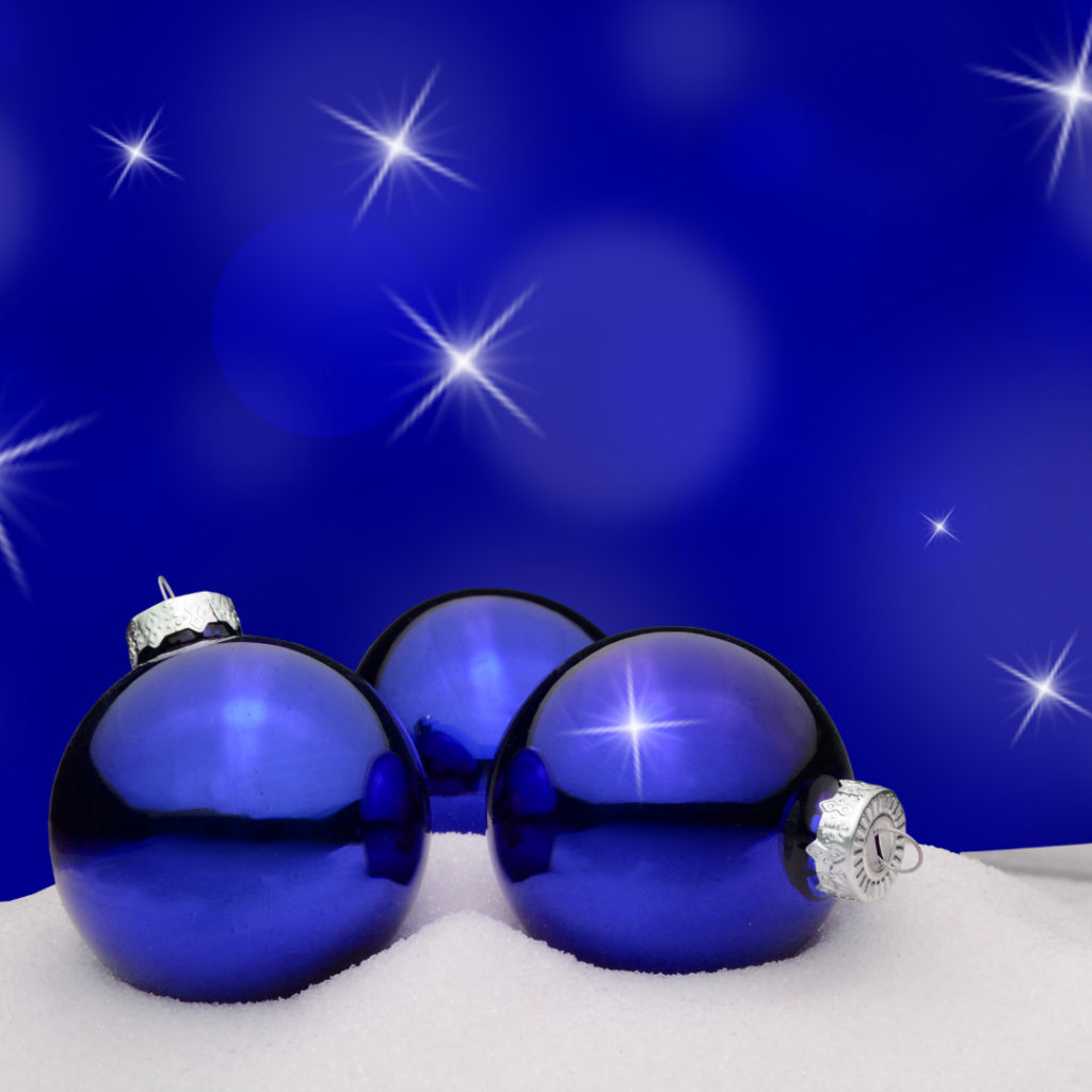 a cobalt blue background and white stars bacground showing 3 large blue Christmas ornaments on a blanket of snow.
