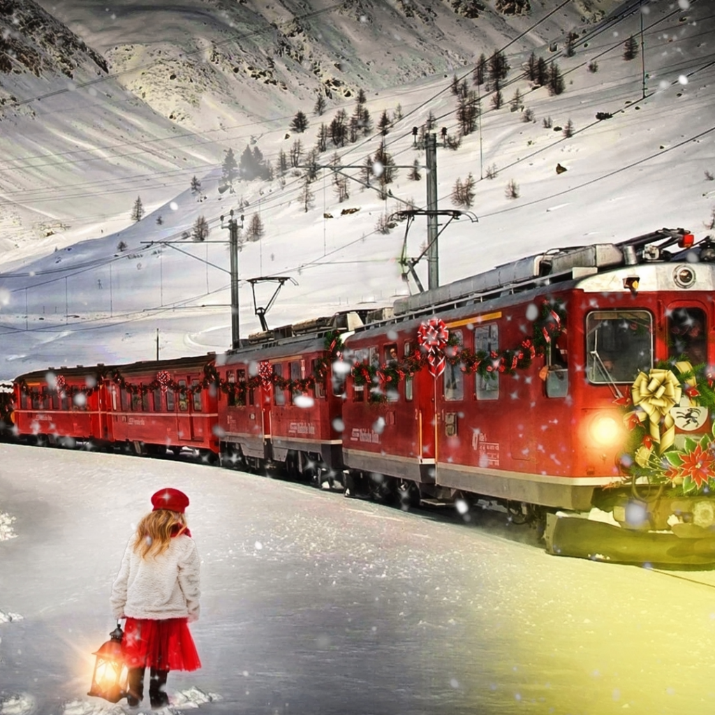 snowy scene of a holiday train chugging down thr track and a little with a red cap and lantern watching train pass